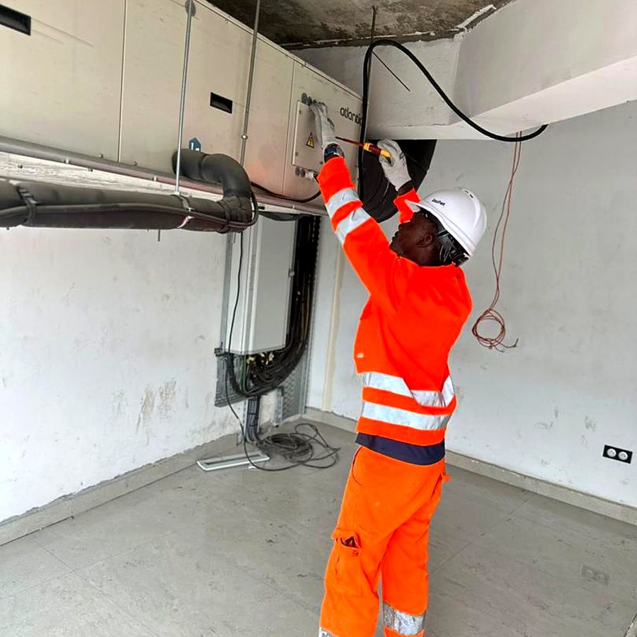 Technician installing ductwork and pipework at ceiling level